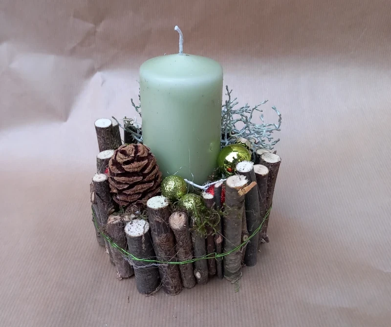 Rundes Gesteck mit Holzstäben, klassische Kerze in creme und Deko.