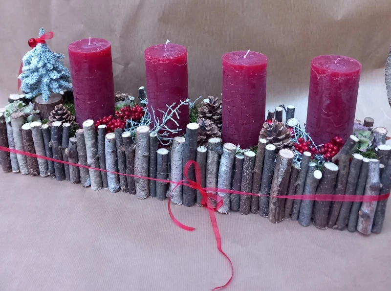 Längliches Gesteck mit Holzstäben und roten rustikal Kerzen.