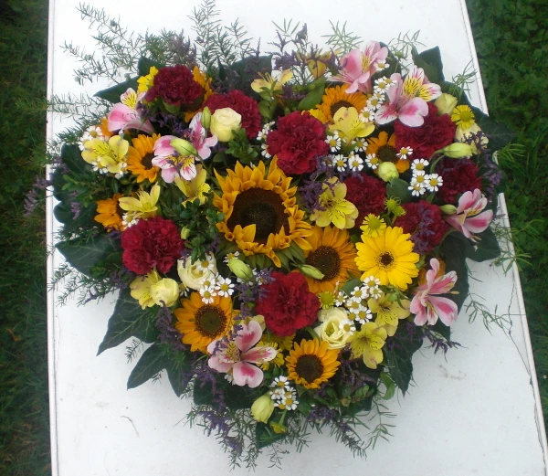 Trauerherz mit großen und kleinen Sonnenblumen, Astromerien, Nelke, Kamille, Helenium, Eustoma, Limonium und Asperagus. Trauerherz mit großen und kleinen Sonnenblumen, Astromerien, Nelke, Kamille, Helenium, Eustoma, Limonium und Asperagus.