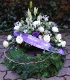 Trauerkranz mit Konifere gewickelt und dekorativ hoch gesteckt mit Rosen, Muscari, Wachsblume, Campanula und Eustoma.