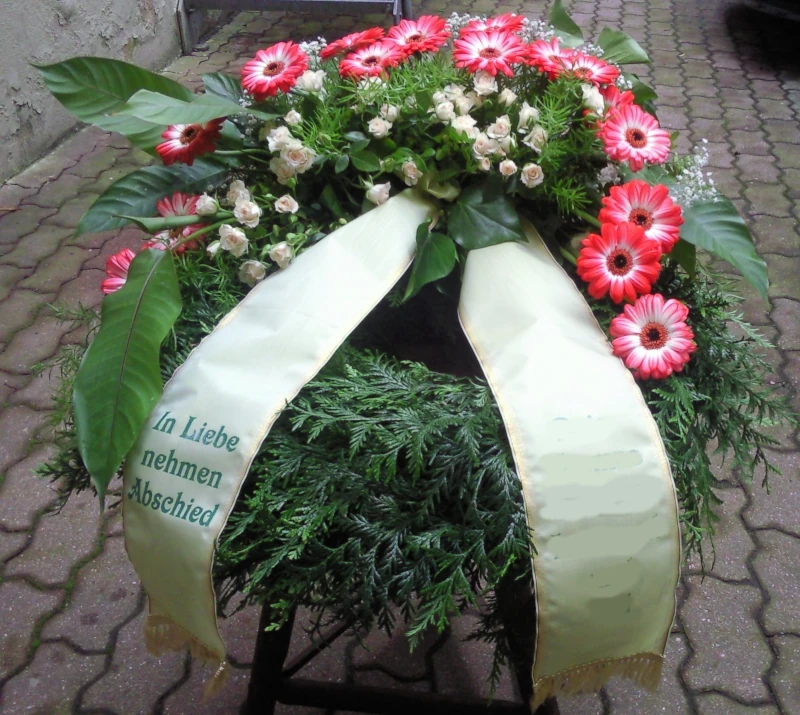 Trauerkranz mit Konifere gewickelt halb hoch gesteckt mit verzweigten Rosen, Gerbera, Schleierkraut und Asparagus. Trauerkranz mit Konifere gewickelt halb hoch gesteckt mit verzweigten Rosen, Gerbera, Schleierkraut und Asparagus.
