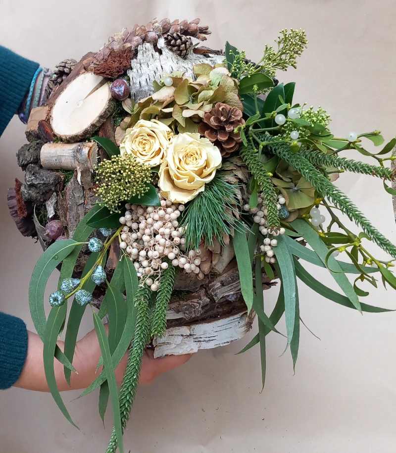 Trauerkugel auf Birkenscheibe mit verschiedenen Rinden und Zapfen, Rosen, Eucalypthus, Zierpfeffer, Mistel, Hortensie und Skimmia.